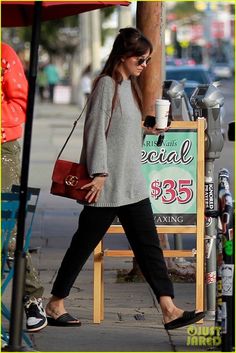 a woman is walking down the sidewalk with her purse