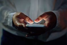 a person holding a cell phone in their hands with the light shining on them,