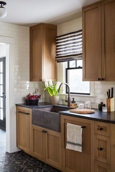 a kitchen with wooden cabinets and black counter tops in front of a window filled with flowers