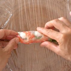 two hands holding food wrapped in plastic