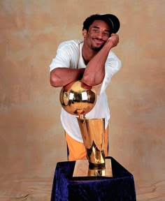 a man posing with a trophy in front of a wall