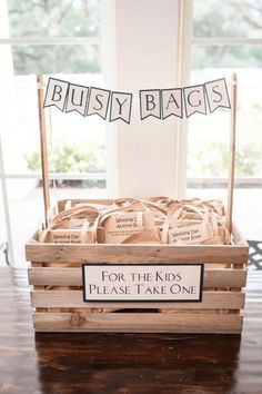 a wooden crate filled with lots of bags on top of a table next to a sign that says busy bags for the kids please take one