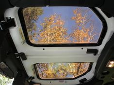 the inside of a vehicle looking up at trees