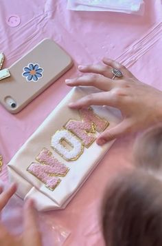 a child is making a cake with the word mom spelled out in gold and pink frosting