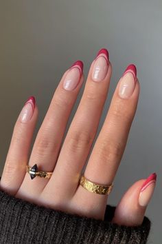 a woman's hand with red and gold manicures on it, holding onto her nails