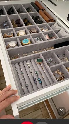 a person is holding an open drawer full of jewelry