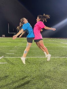 two girls playing soccer on a field at night