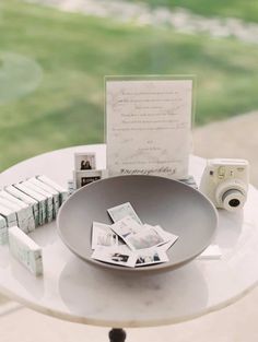 a table topped with a bowl filled with lots of cards next to an open camera