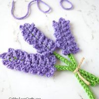 three crocheted flowers sitting on top of a white table next to a string