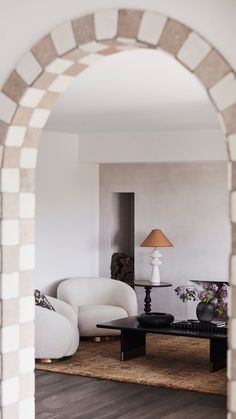 a living room filled with furniture and a lamp on top of a wooden table next to a white couch