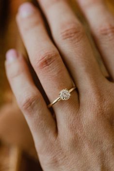 a woman's hand with a diamond ring on top of her finger and the other hand holding it