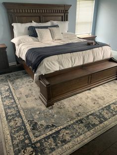 a large bed sitting in the middle of a bedroom on top of a blue rug