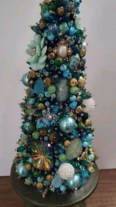 a blue christmas tree with ornaments on it's top and green base, sitting on a table