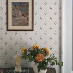 a vase filled with yellow flowers sitting on top of a table next to a painting