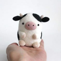 a hand holding a small stuffed cow in it's palm