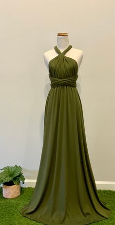 a dress on display in front of a white wall and potted plant next to it