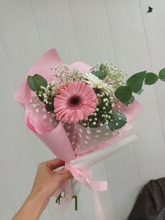 a person holding a pink and white flower bouquet