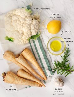 the ingredients for cauliflower are laid out on a white marble counter top, including broccoli, lemons, olive oil, garlic and parsley