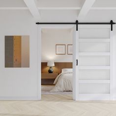 an open door leading to a bedroom with white walls and wood floors, along with a bed in the background