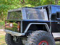 a large black truck parked on top of a lush green forest filled with lots of trees