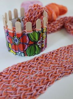 some knitting needles and yarn on a white table with an orange flowered basket next to it