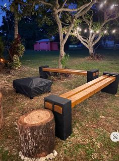 a wooden bench sitting in the middle of a field next to a tree stump with lights on it