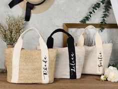 three personalized jute bags sitting on top of a wooden table next to flowers