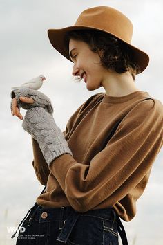 a woman wearing a hat and holding a bird