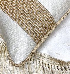 a white and gold pillow with fringes on it