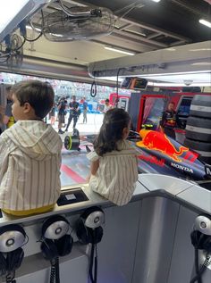 two children are looking at the red bull racing car