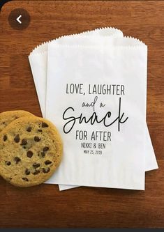 two chocolate chip cookies sitting next to each other on top of white paper bags that say love, laughter and a snack for after