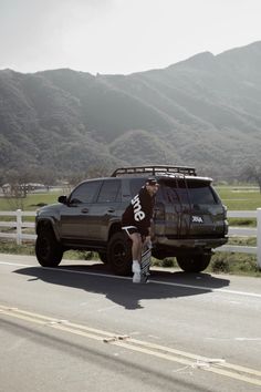 a man riding a skateboard next to a parked truck on the side of a road