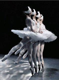 three ballerinas in white tutus with their arms extended