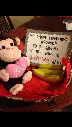 a stuffed monkey sitting on top of a table next to bananas and a sign that says no more monkeys around