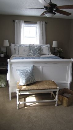 a white bed with blue and white pillows on top of it next to a window