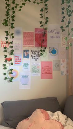 a bed with pillows and plants hanging from the wall above it, along with posters on the wall