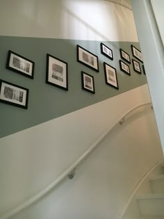 there are many framed pictures on the wall next to stairs and railings in this room