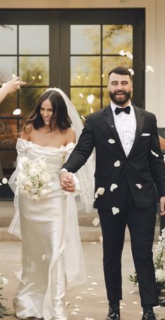 a bride and groom are walking down the aisle with petals in the air as they exit their wedding ceremony