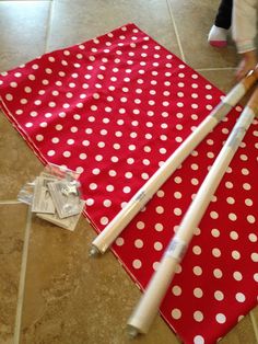 two baseball bats laying on top of a red and white polka dot cloth