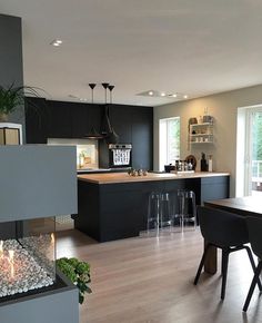 an open kitchen and dining room area with wood flooring, black cabinets and fireplace