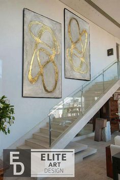 two paintings hanging on the wall next to a stair case