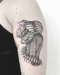 a woman's arm with a black and white snake tattoo on the left shoulder