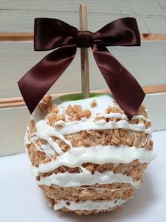 an apple covered in white frosting and topped with a brown bow sitting on top of a table