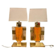 a pair of orange glass table lamps sitting on top of a metal base