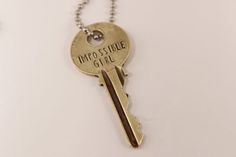 a gold key with the words impossible girl on it is hanging from a ball chain