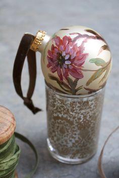 an ornament sitting on top of a glass vase next to thread spools