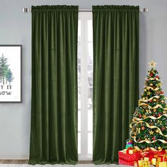 a christmas tree sitting in front of a window with green curtains and presents under it