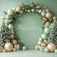 two christmas trees and presents in front of a green wall