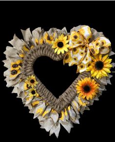 a heart - shaped wreath with sunflowers and burlocks is displayed against a black background