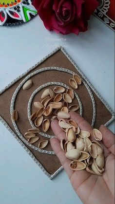 someone is holding some nuts in their hand next to a rose and other items on the table